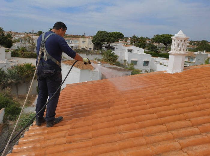 Trabalhador limpa um telhado com água sob pressão