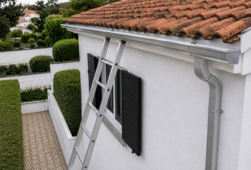 Escada encostada à fachada de uma casa para proceder à limpeza das calhas