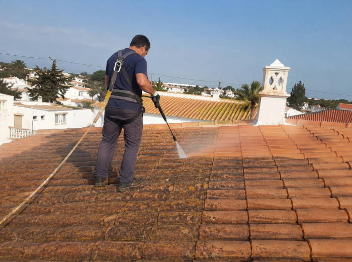 Trabalhador a limpar o telhado de uma casa em Faro